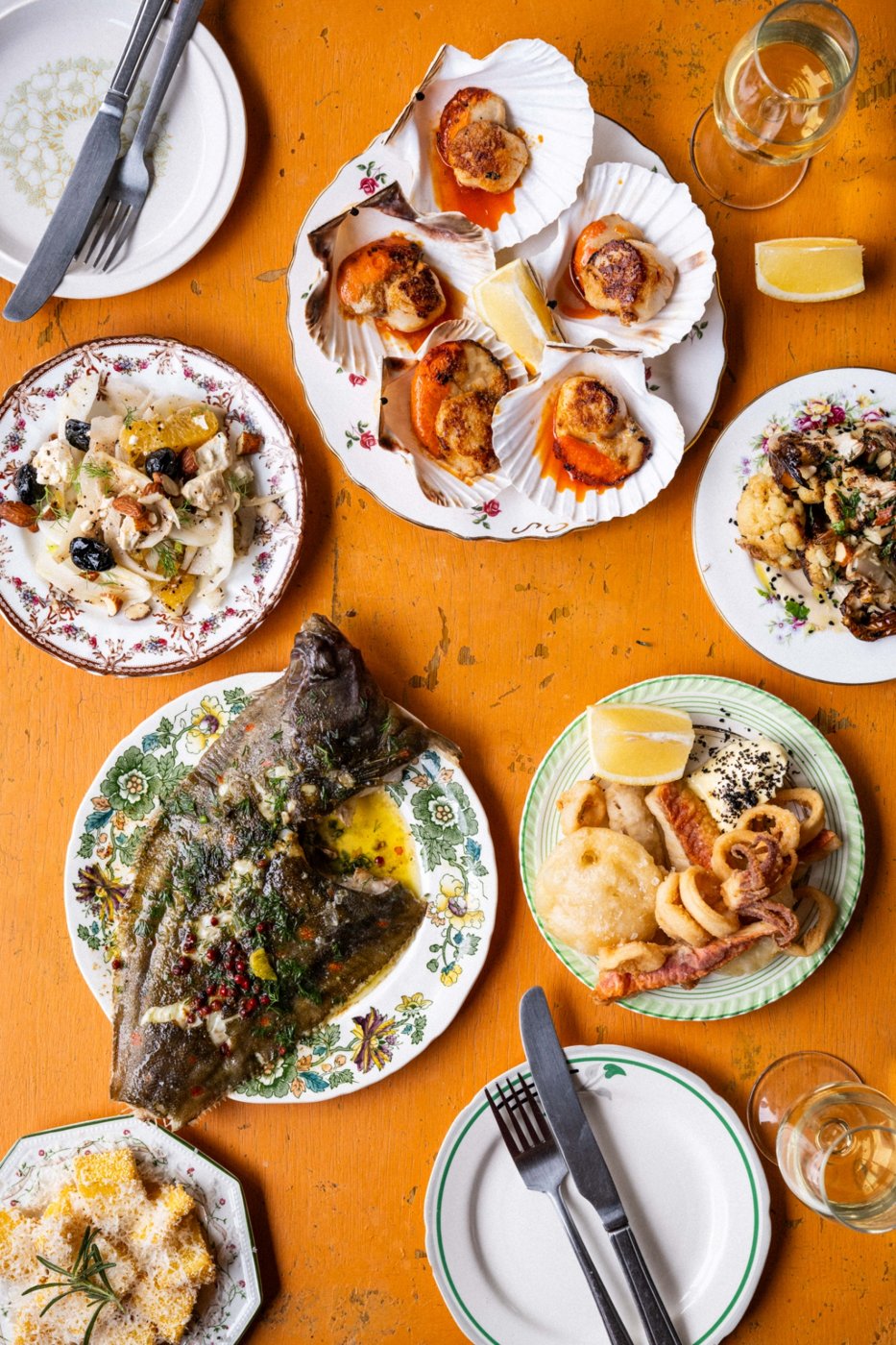 Scallops with nduja butter, fennel and olive salad, whole flat fish and fried squid on vintage plates